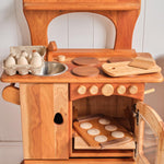 Wooden play kitchen accessory set with eggs, metal bowl, cookie trays, and cutting boards