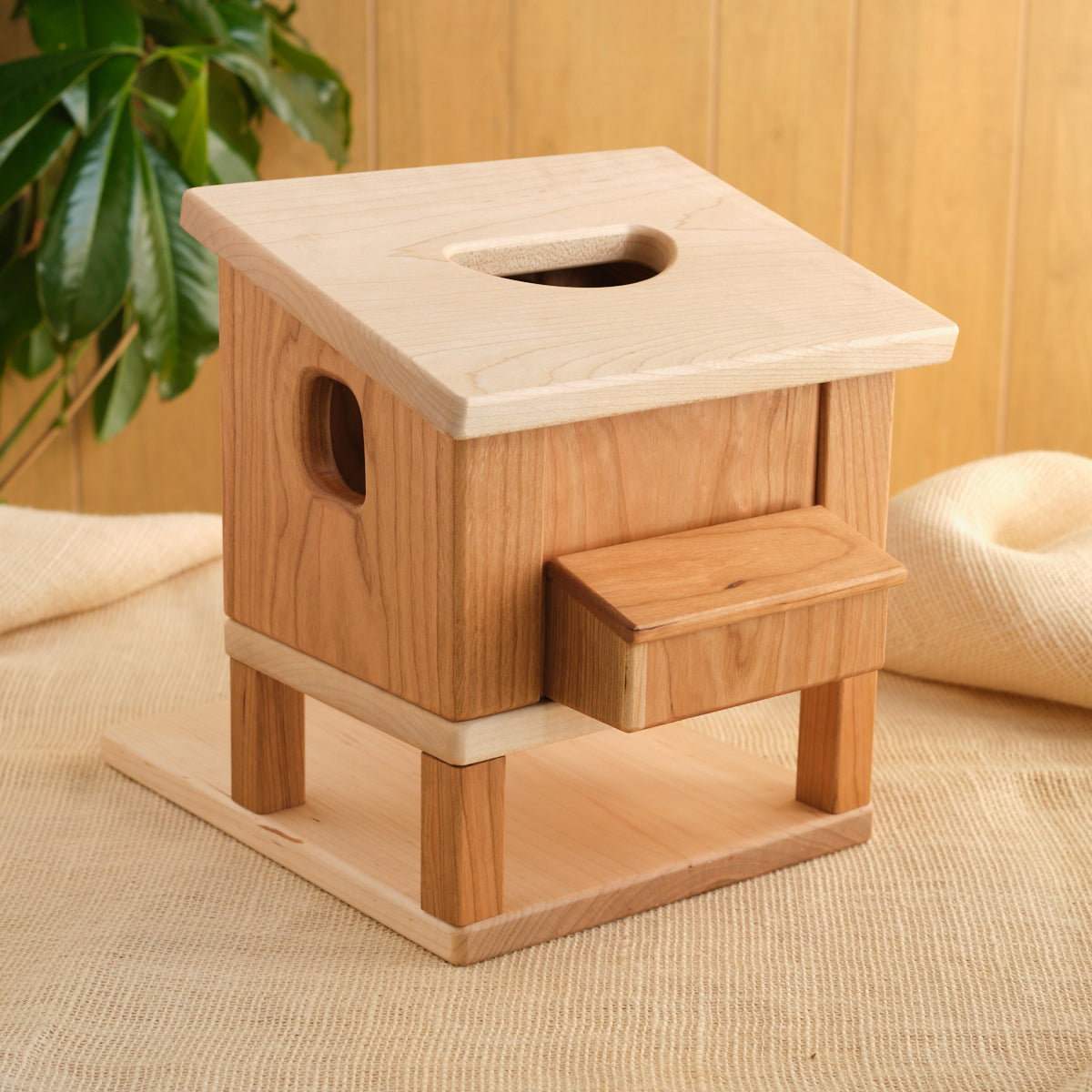 Wooden hen house with round hole on top and side ramp steps