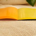 Open yellow and orange kite paper sheets showing square-fold star patterns