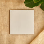 Single white kite paper square sheet on burlap with green leaves at top