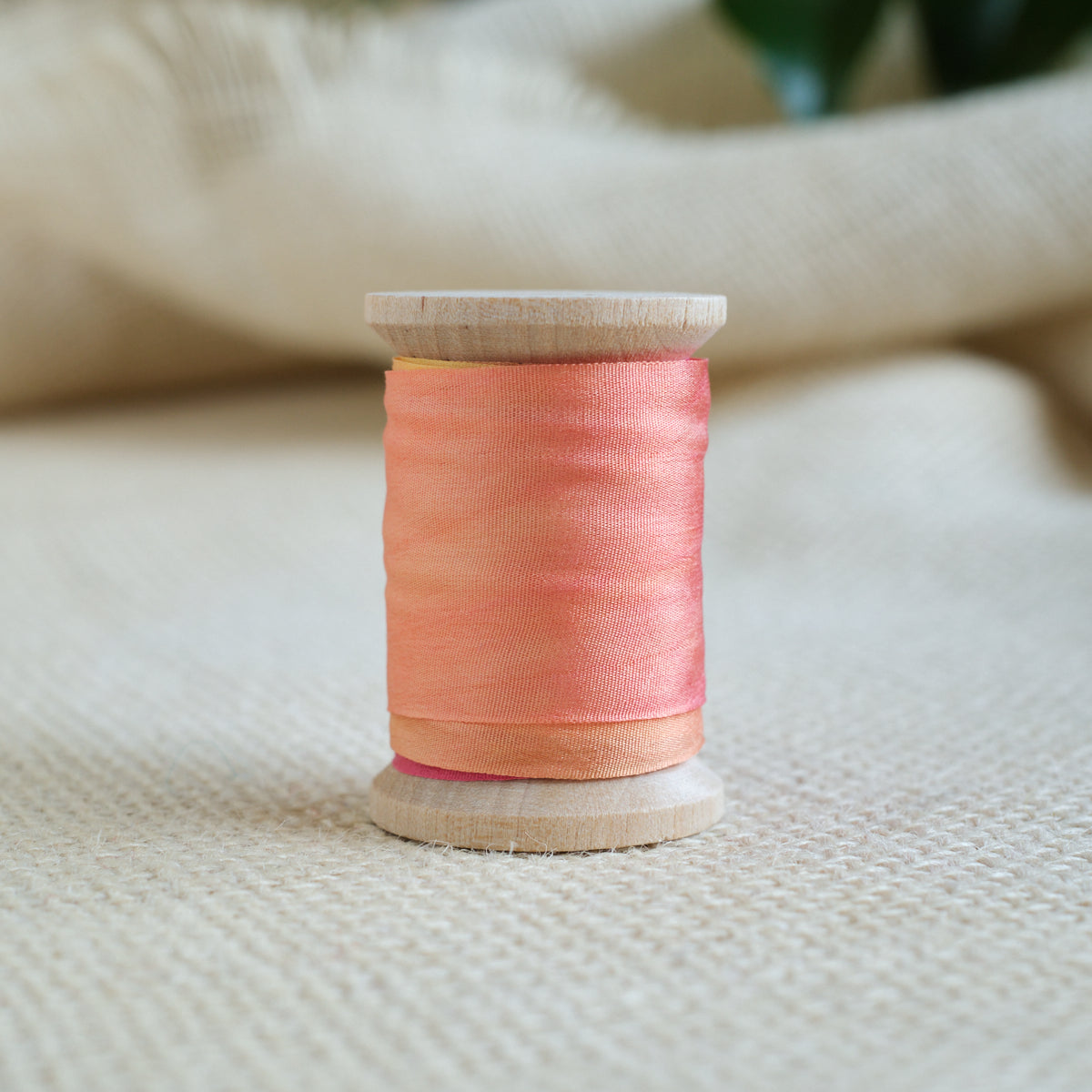 Orange silk ribbon spool on wooden base