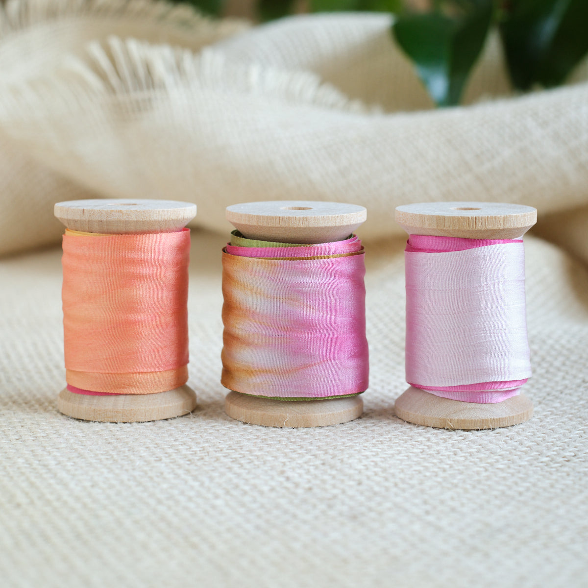 Three silk ribbon spools: pink, orange, and multicolor