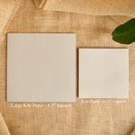 Kite paper 6.25" squares: two beige sheets on burlap with a green leaf